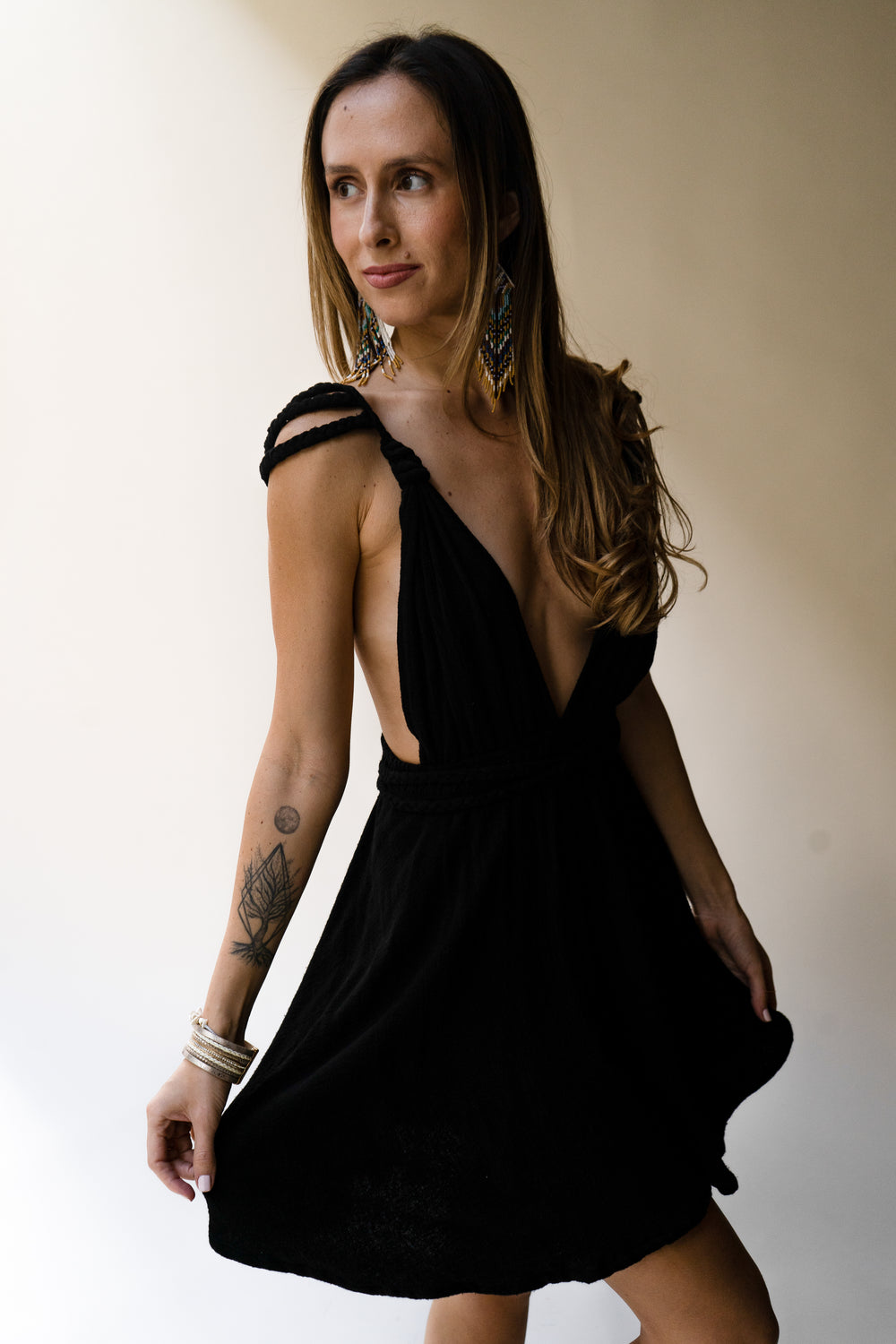 Woman wearing a black dress with braided shoulders against a plain background in goddess style
