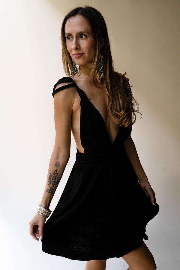 Woman wearing a black dress with braided shoulders against a plain background in goddess style